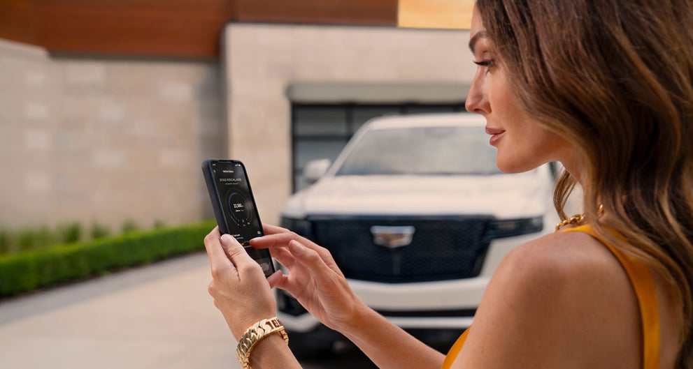lady checking her mobile with a Cadillac vehicle background | Prestige Cadillac in WARREN MI
