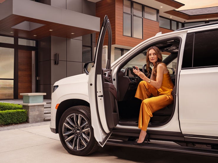 A woman stepping out of a Cadillac in front of a home