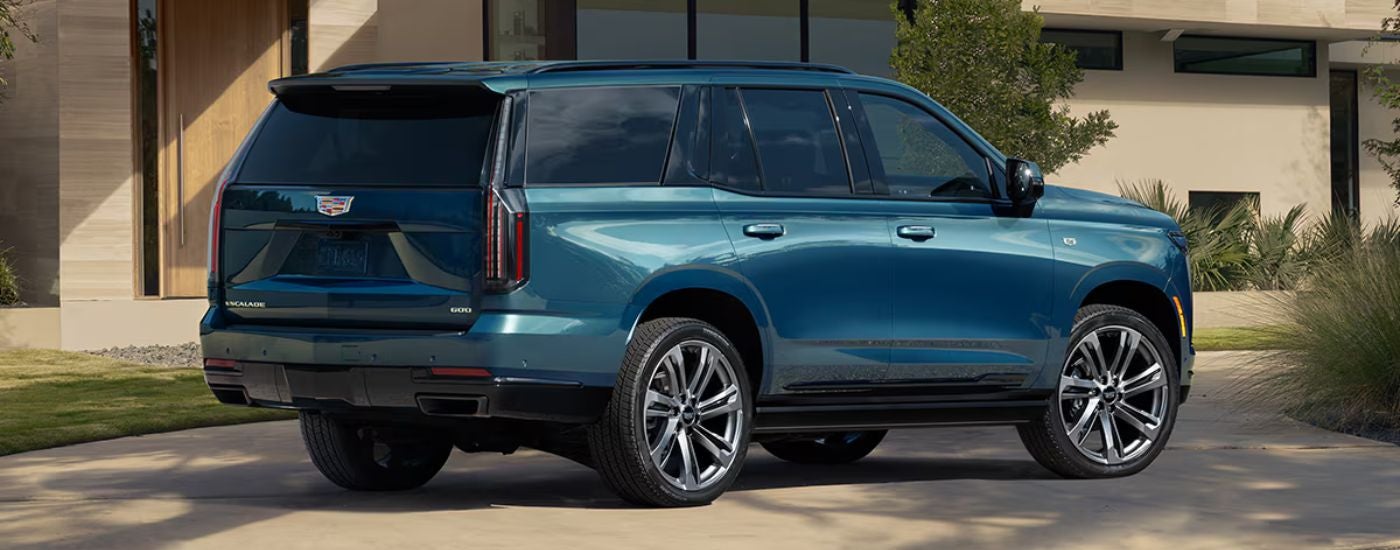 Side view of a blue 2026 Cadillac Escalade parked in a driveway.