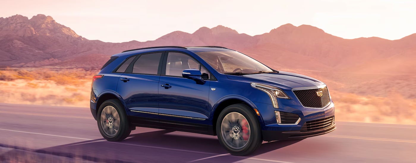 Blue 2026 Cadillac XT5 driving down an open road.