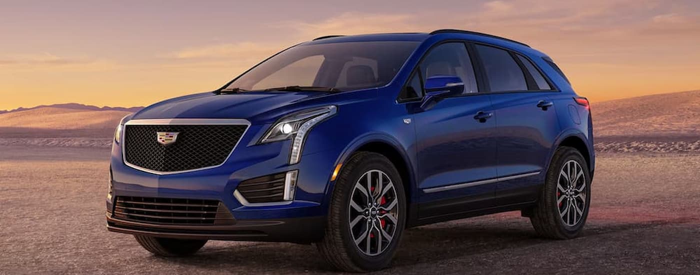 A blue 2026 Cadillac XT5 parked off-road at sunset