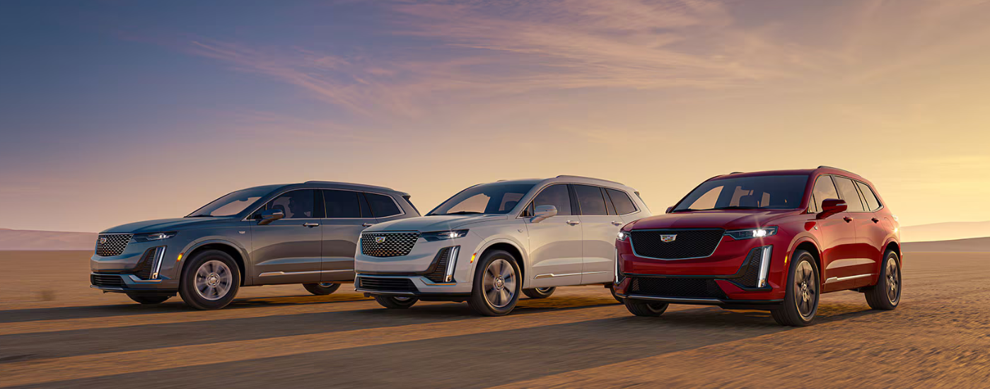A silver, a red, and a blue 2026 Cadillac XT6's driving side by side