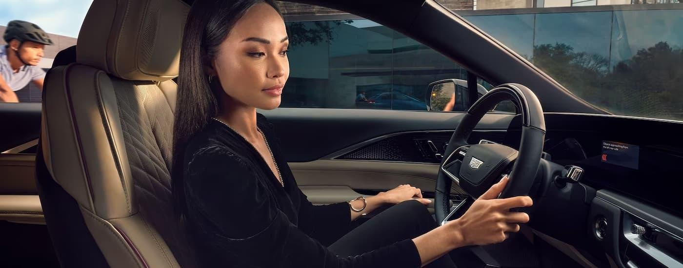 A woman is in the driver's seat of a 2025 Cadillac LYRIQ during a test drive at a Cadillac dealer.