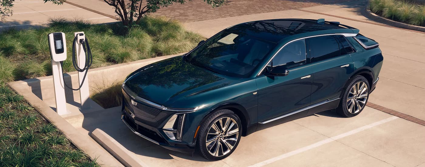 A blue 2025 Cadillac LYRIQ is parked in a sparking spot next to a charging station.