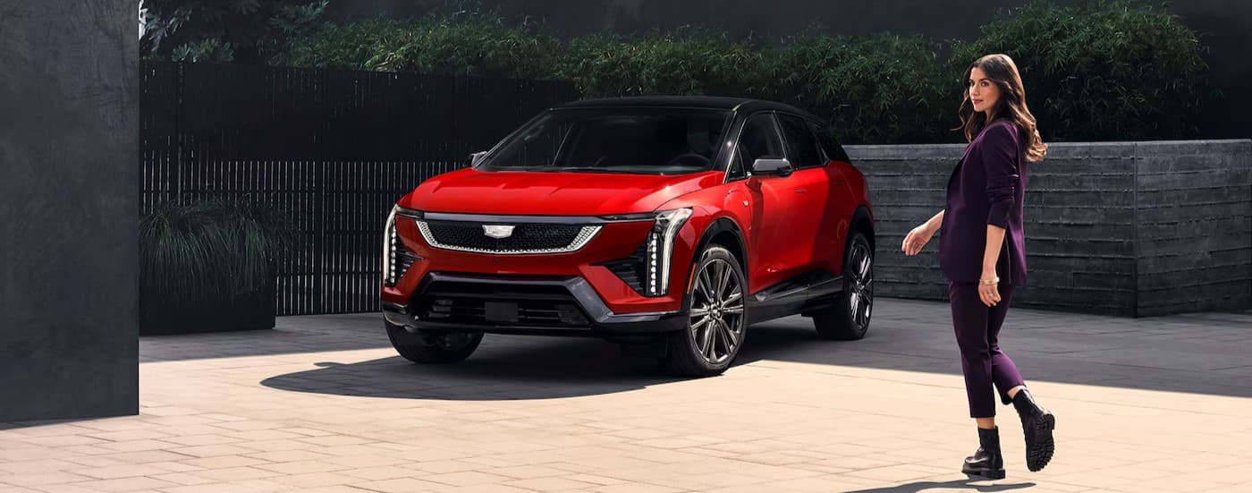 A person walking near a red 2026 Cadillac OPTIQ.