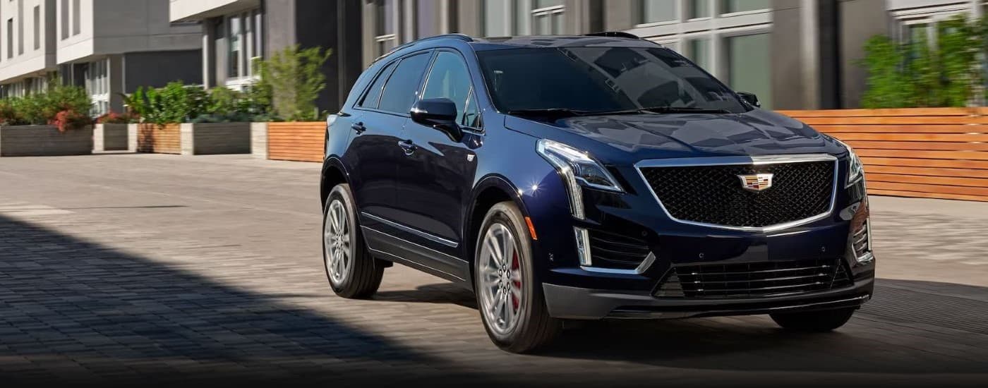 A dark blue 2023 Cadillac XT5 for sale driving down an open road.