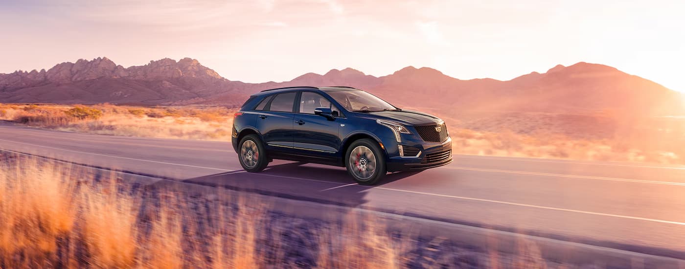 A dark blue 2025 Cadillac XT5 driving on an open road.