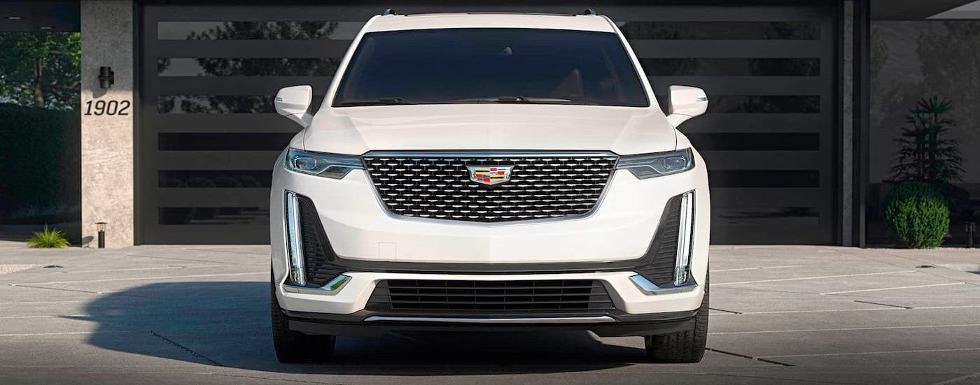 A white 2025 Cadillac XT6 parked near a garage.