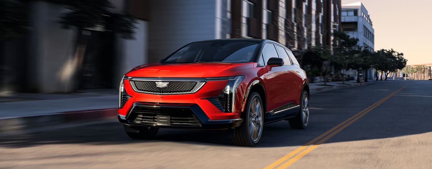 A red 2026 Cadilla OPTIQ driving down a city street