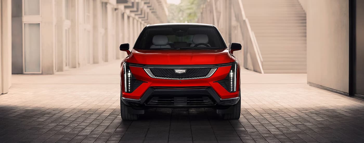 A red 2026 Cadillac OPTIQ parked off-road on cobblestone