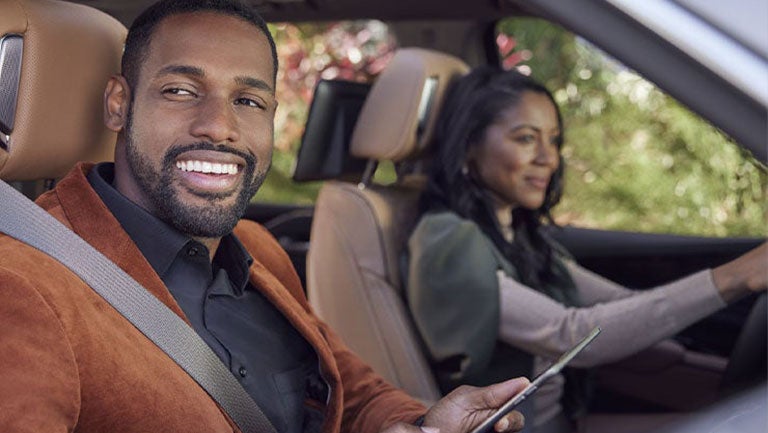 A woman driving a vehicle with the man passenger looking out the window