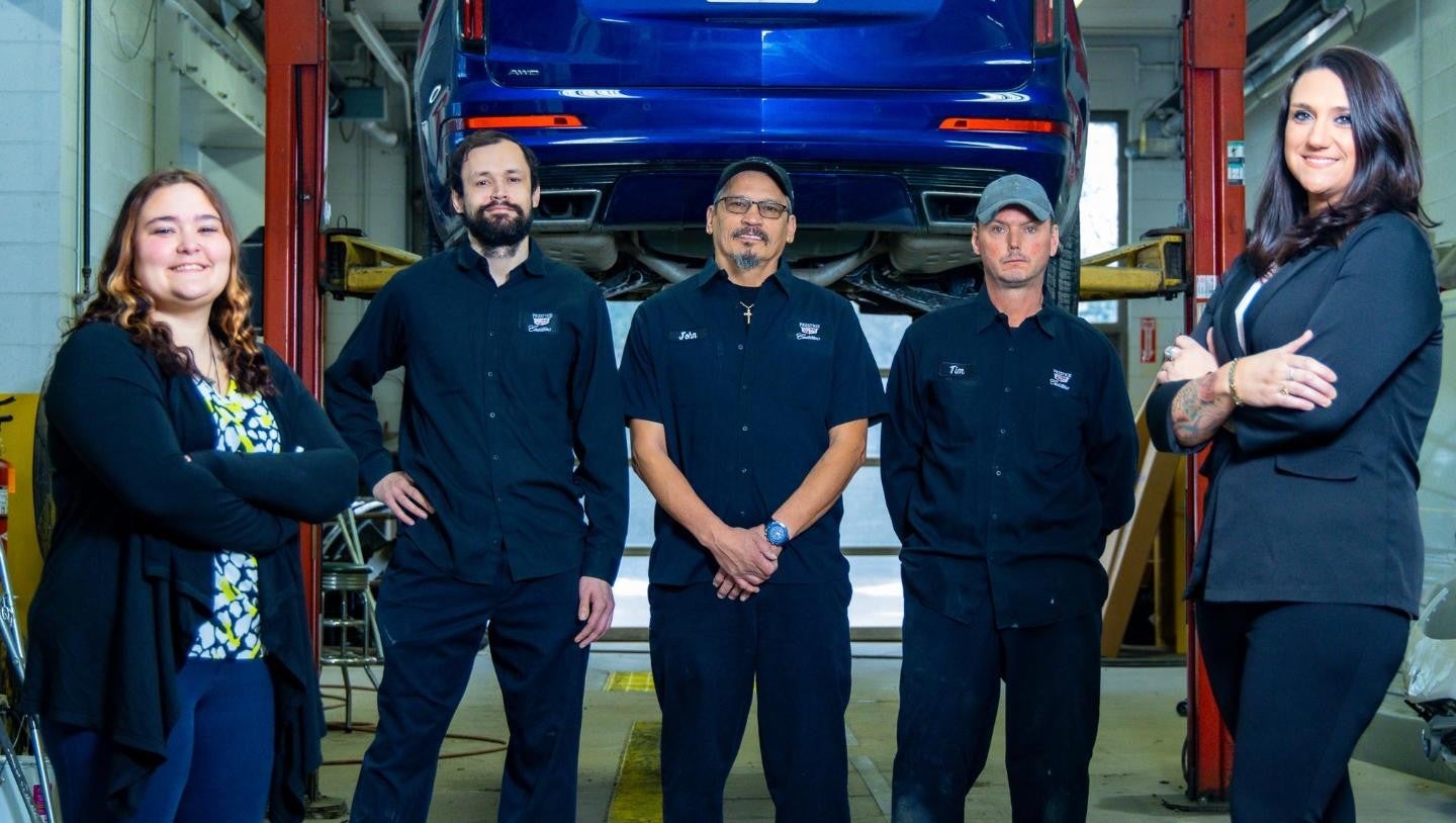 Prestige Cadillac Maintenance team posing in front of an elevated vehicle