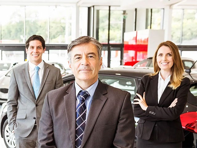 A team of vehicle salespeople standing in their showroom